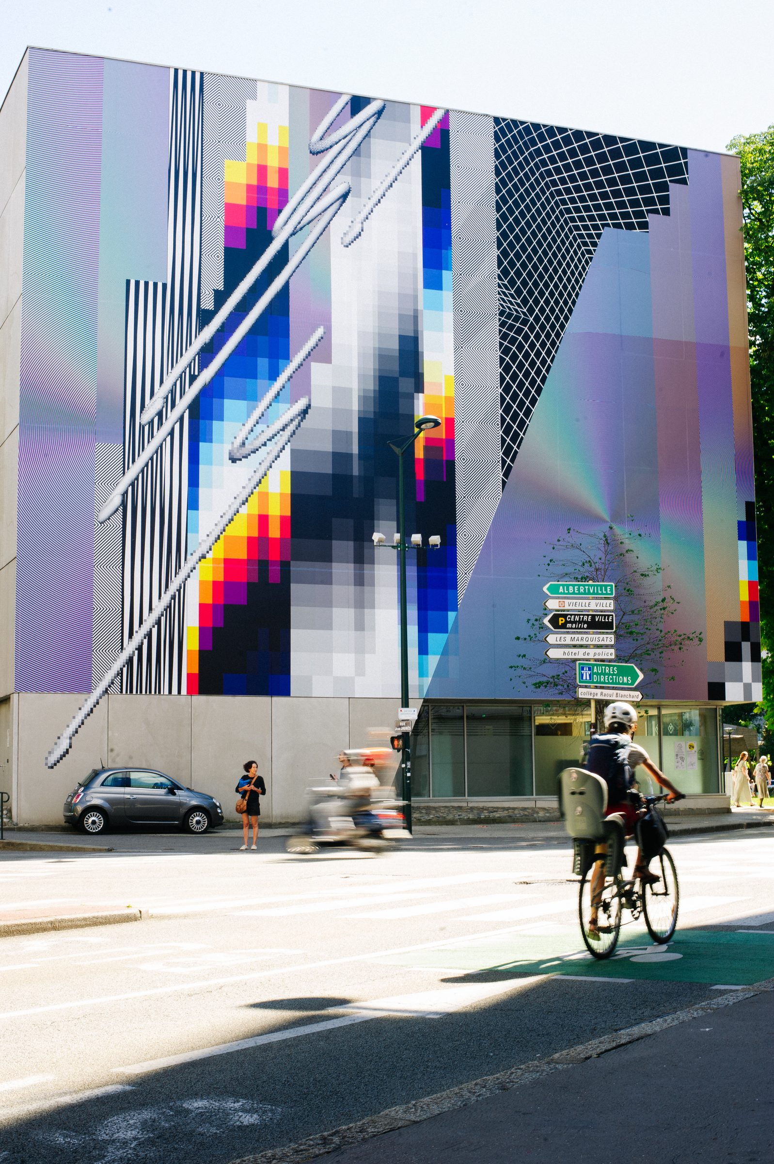 Optichromie Annecy, 2022 — La esquina del edificio, con la ciudad pasando por delante