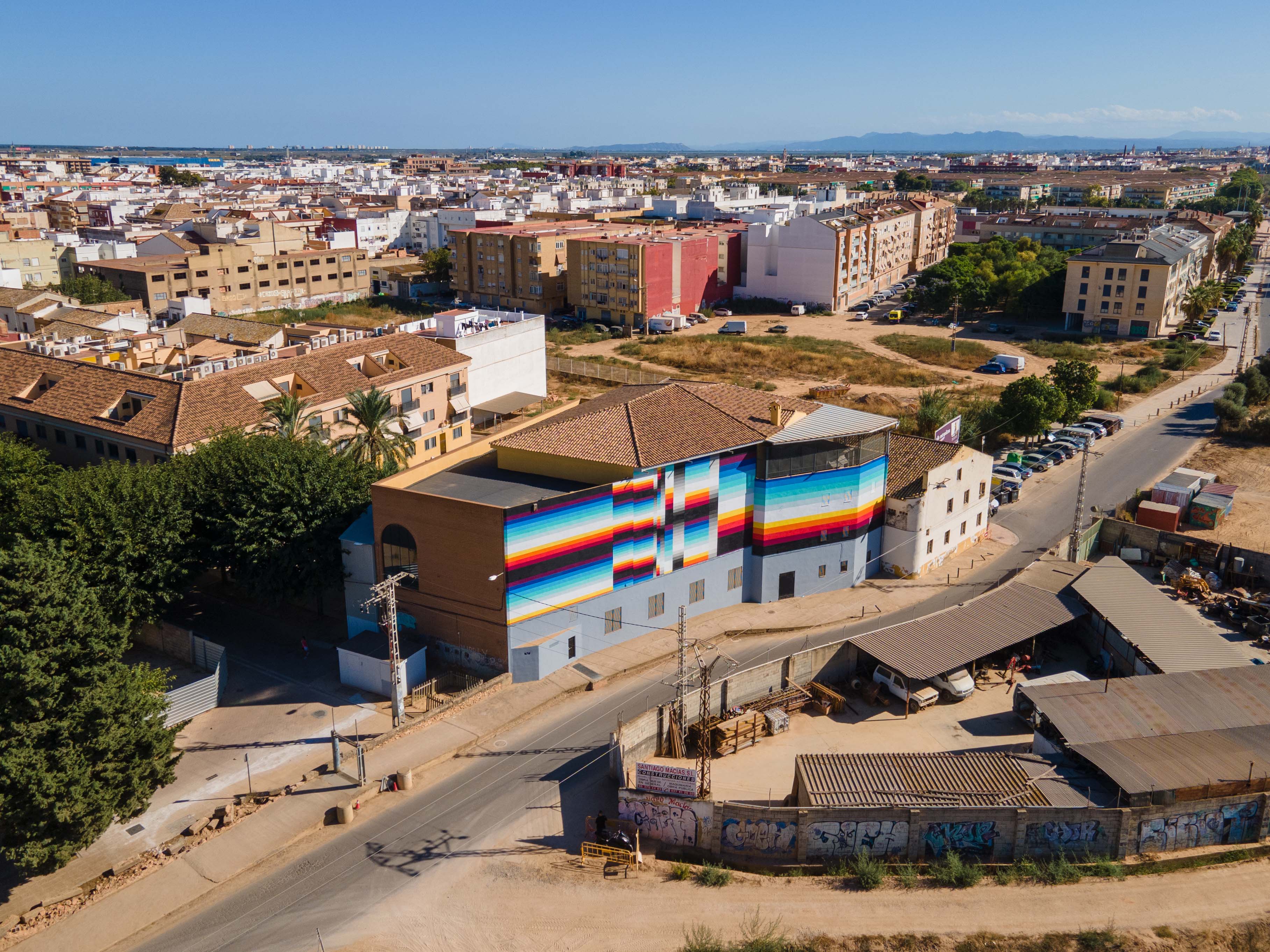 TERRA DE VALENTIA. Estabilidad – Interrupción – Claridad, 2025 — Vista aérea: el mural sobre el edificio, con el pueblo de Benetússer alrededor.
