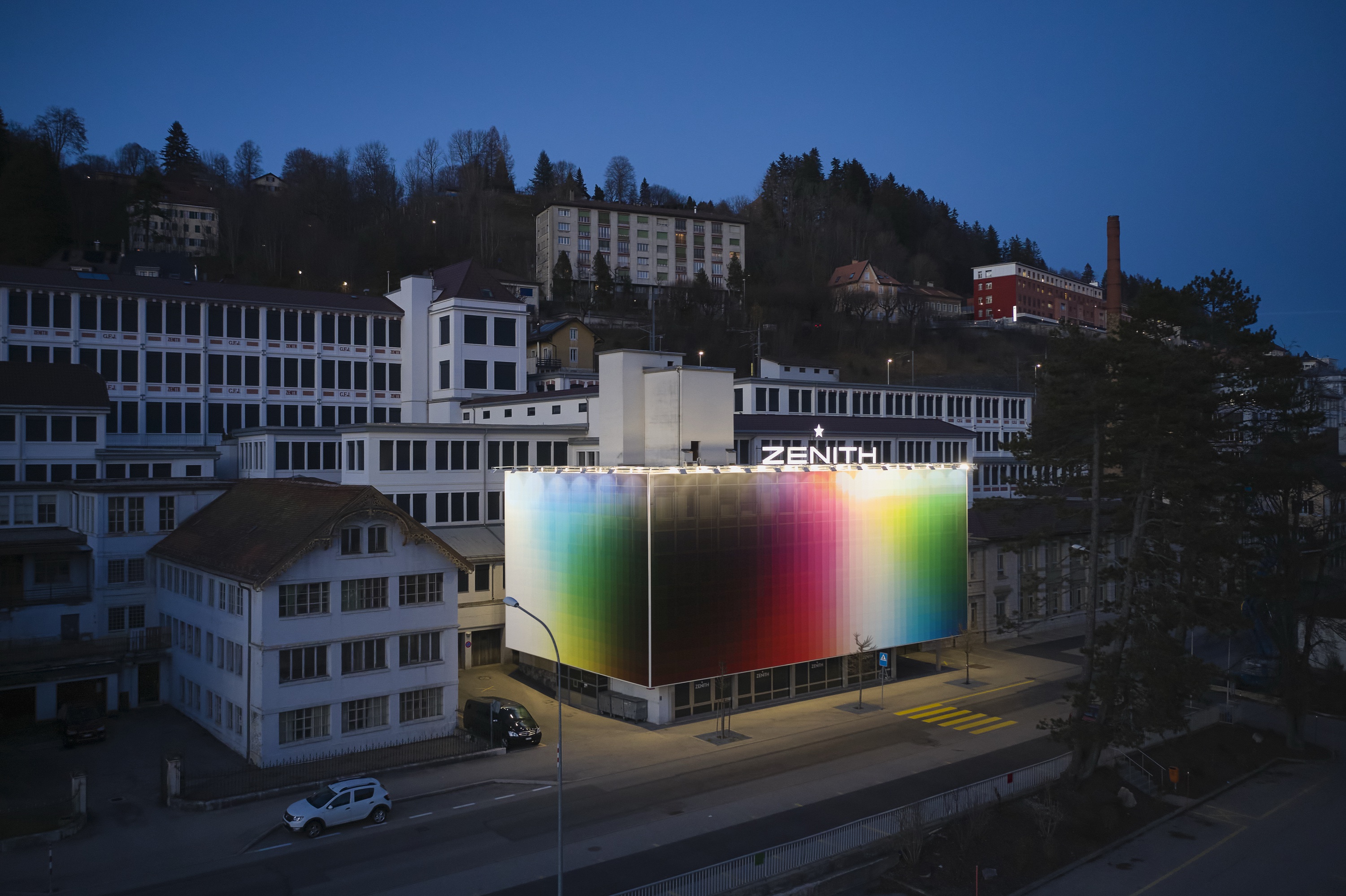 Zenith Manufacture facade, 2020 — Aérea nocturna: la fachada arcoíris sobre Le Locle.