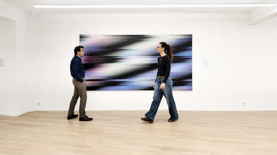 Chromadynamica 133 (2021), panel horizontal de 150 × 300 cm con bandas diagonales en negro, violeta y azul, en la sala de Danysz con dos visitantes delante