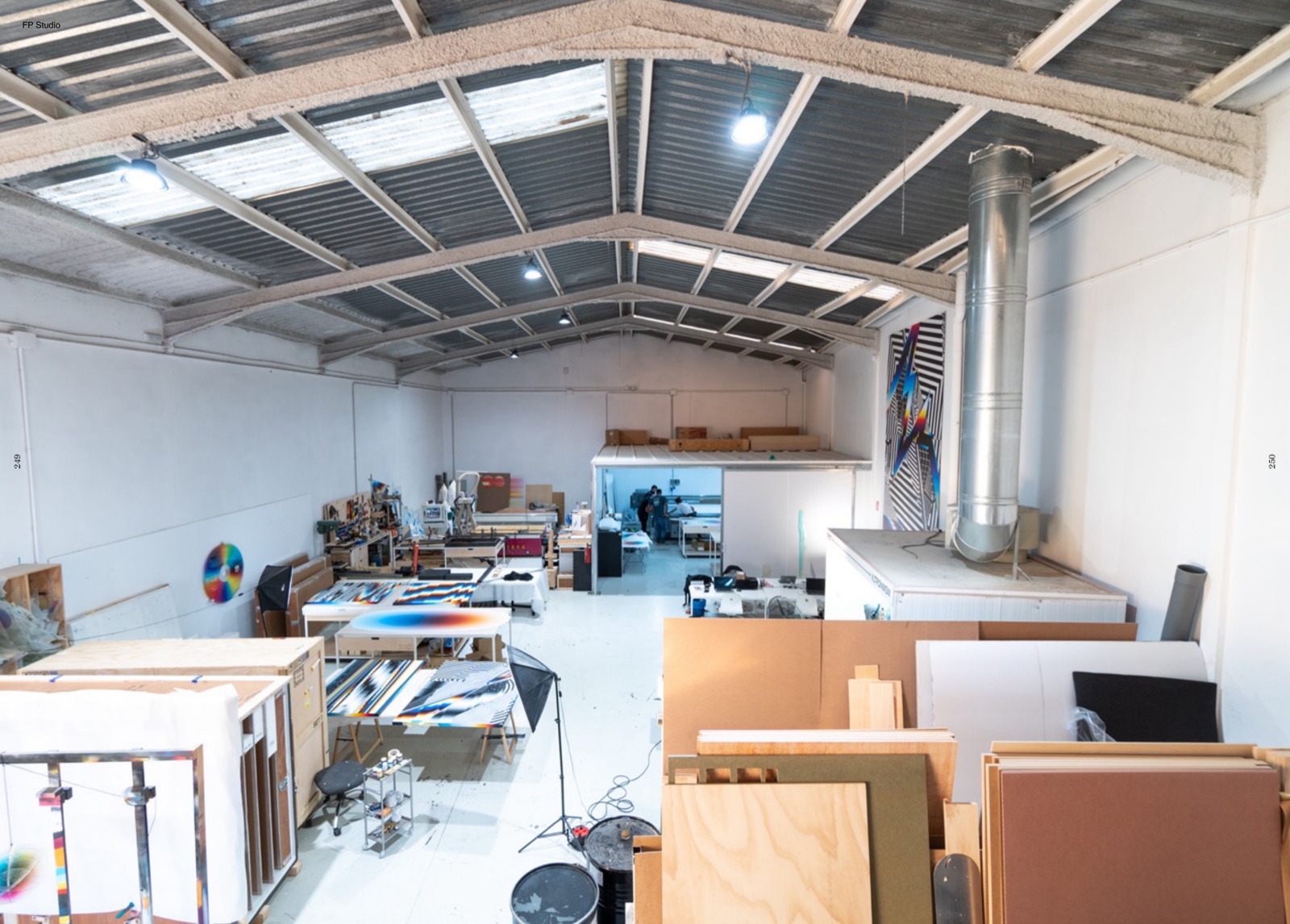 La nave de FP Studio: obra en producción, cajas de embalaje, luz de día. Dieciséis individuales en trece países en cinco años salen de aquí — ese ritmo lo sostiene el equipo.